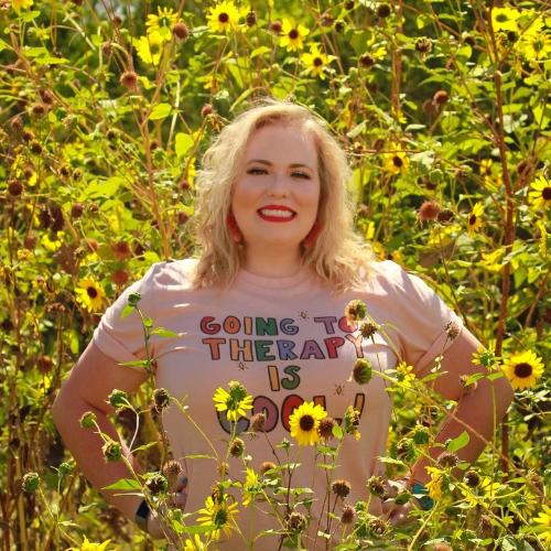 Dr. Nichole Vincent standing in a sunflower field wearing a shirt that says "Going to therapy is cool" — representing a modern, compassionate approach to online therapy